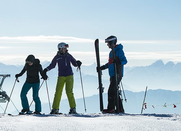 3 Skifahrer zihen die Ski an.